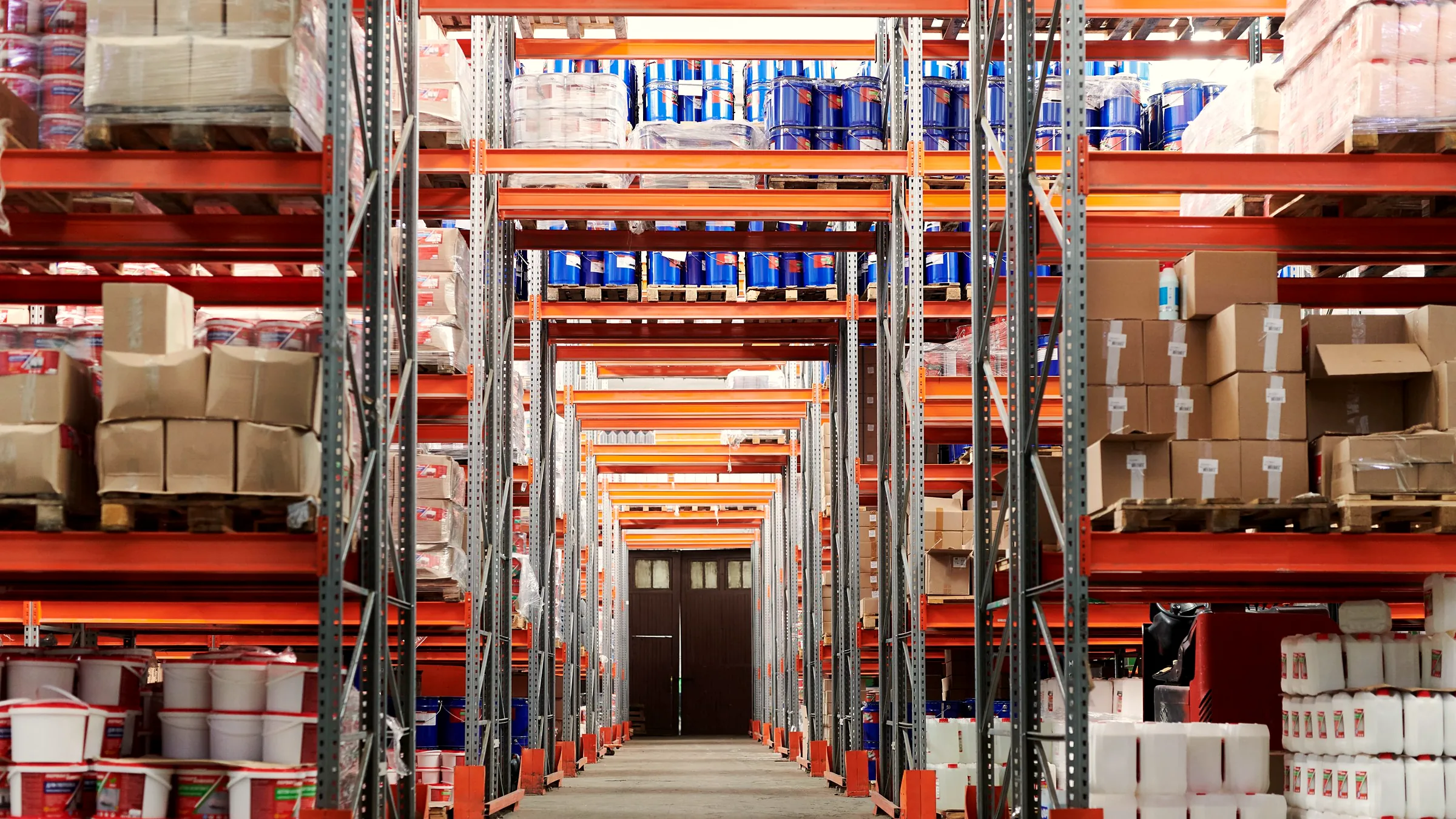 Wide aisle between high industrial racks in a packaging warehouse