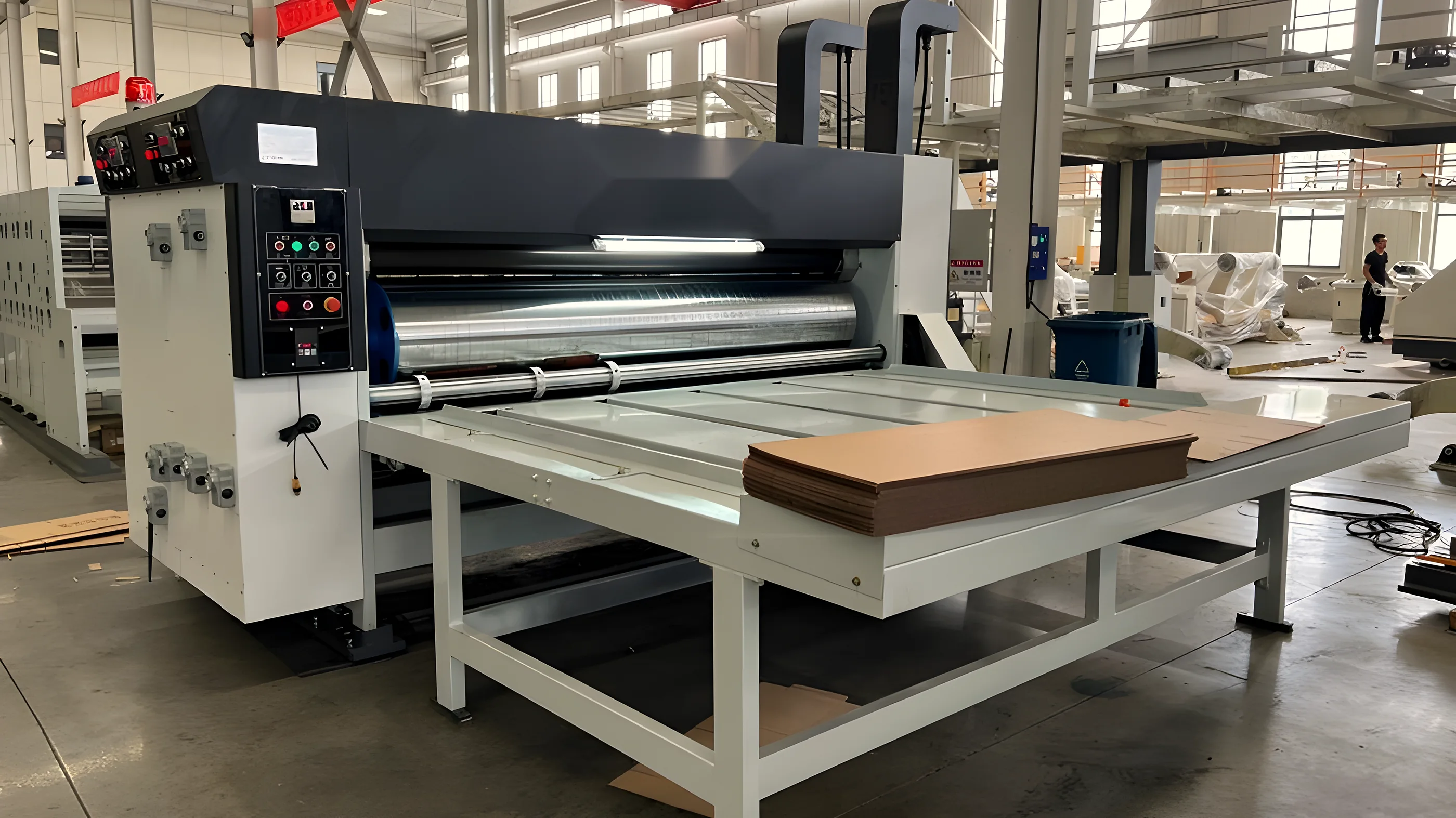 Printer slotter on a packaging factory floor with corrugated board on the feed table