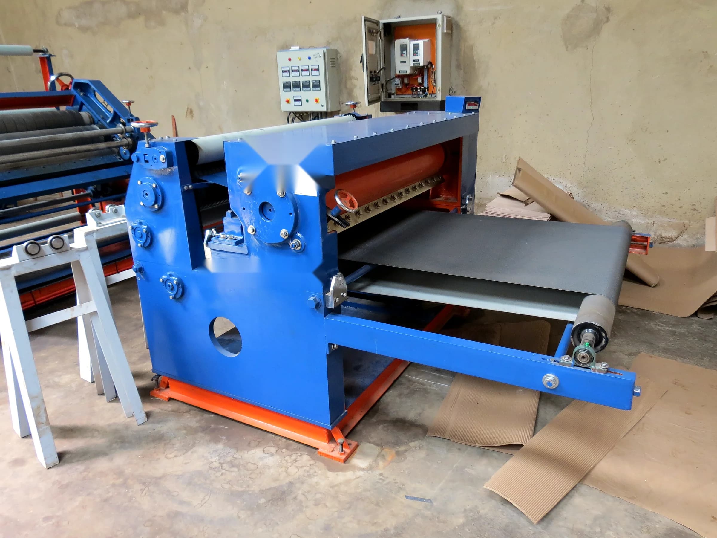 Corrugating and converting machine with conveyor on a factory floor